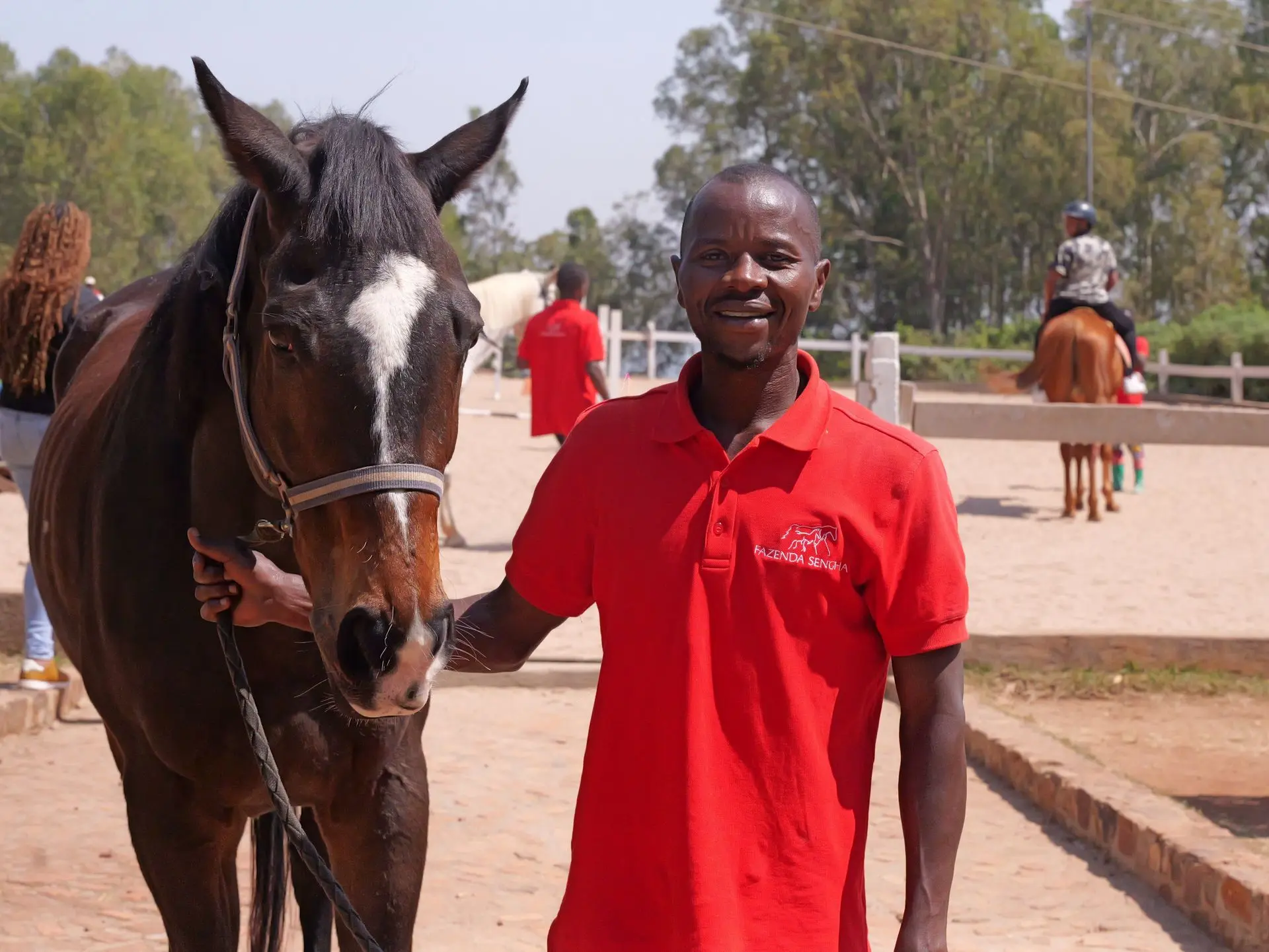 Innocent standing with a horse in the riding arena.
